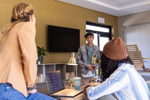 Young professionals collaborating around long table in modern coworking space teamwork