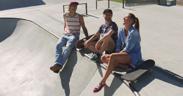 Group of three friends sitting at skate park, each with a skateboard. They are laughing and enjoying the sunny day while relaxing next to the skate ramps. Ideal for advertisements showcasing youth lifestyle, friendship, outdoor activities, and leisure. Can be used for social media campaigns targeting young audiences.