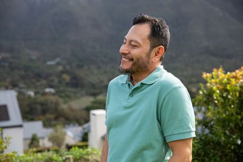 Middle-aged asian man smiling on suburban hillside wearing mint-green polo lifestyle