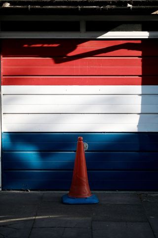 Traffic Cone against Tri-Color Striped Background on Sidewalk