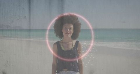Afro-haired woman on beach with futuristic glowing ring