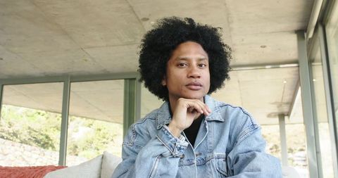 Contemporary african american man wearing denim jacket resting chin in minimalist interior