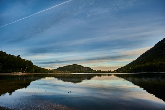 Capturing the calmness of a mountain lake at sunset with reflective waters. Ideal for use in travel brochures, nature and outdoor adventure magazines, environmental awareness campaigns, and home decor featuring landscape photography.