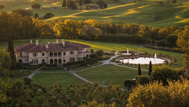 Mediterranean villa estate at golden hour with formal gardens, reflecting ponds and fountain