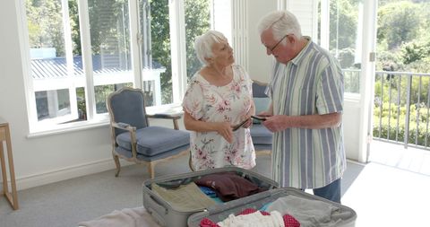Senior Couple Packing Suitcase for Vacation at Home