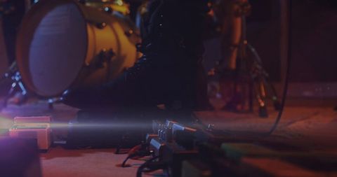 Musician Activating Guitar Pedals on Dimly Lit Stage