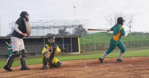 Female softball player swinging bat during competitive game