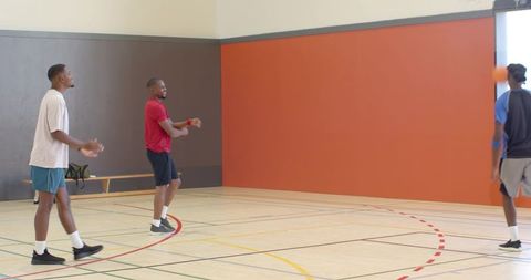 Men practicing basketball passing and dribbling on indoor gym court during training session