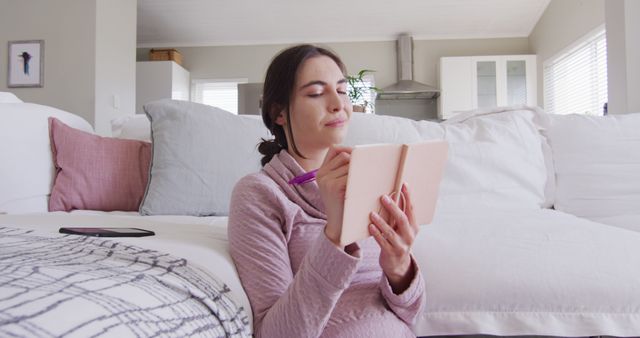 Happy caucasian woman sitting on floor and taking notes - Download Free Stock Photos Pikwizard.com