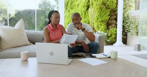 Couple Reviewing Finances Together While Using Laptop and Smartphone
