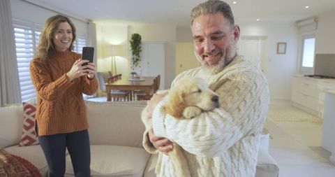 Smiling couple enjoying new golden retriever puppy in cozy living room