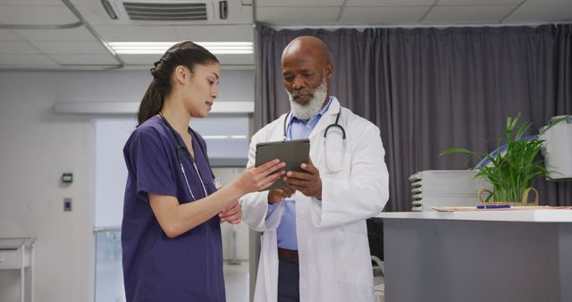Diverse male and female doctors using tablet and talking at hospital. Medicine, healthcare, lifestyle and hospital concept.