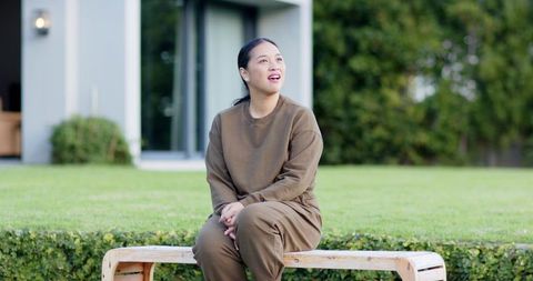Woman in Brown Outfit Daydreaming on Garden Bench