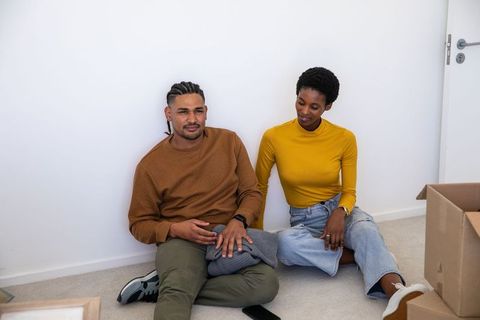 Diverse Couple Relaxing on Floor Amid Unpacked Moving Boxes