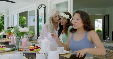 Women Enjoying Tea and Conversation with Colorful Pastries