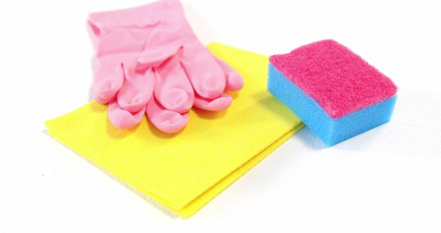 Colorful cleaning supplies including pink rubber gloves, a yellow cloth, and a blue and pink sponge. Ideal for topics about hygiene, sanitation, household chores, and domestic cleaning routines. Can be used in articles, advertisements, and instructional materials related to home maintenance, cleanliness, and stain removal.