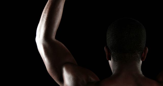 Strong Male Figure Raising Arm Against Black Background - Download Free Stock Images Pikwizard.com
