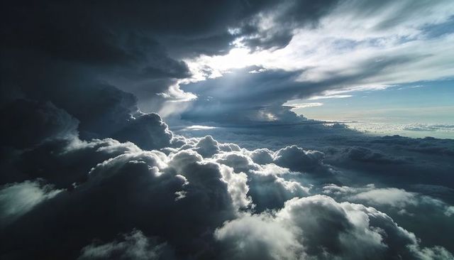 Sunbeams Piercing Towering Cumulonimbus Over Dramatic High-Altitude Stormfront Cloudscape