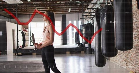 Woman skipping rope in boxing gym with performance graph overlay for fitness tracking