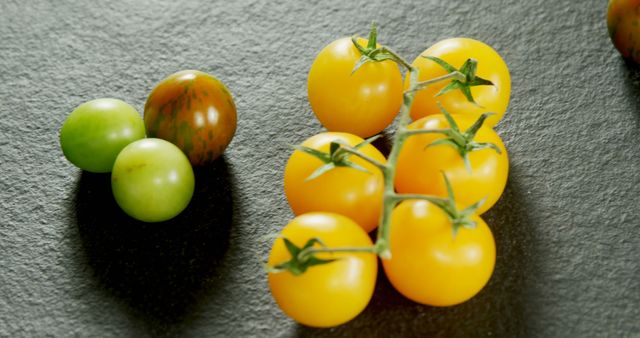 Various colorful cherry tomatoes arranged on a slate surface. Perfect for themes related to fresh produce, healthy eating, vegetarian cuisine, and organic gardening. Suitable for use in food blogs, recipe websites, culinary magazines, and health articles.