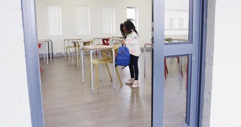 African american student entering classroom with blue backpack