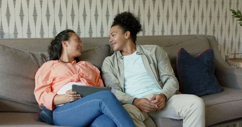 Smiling Couple Relaxing on Sofa with Tablet