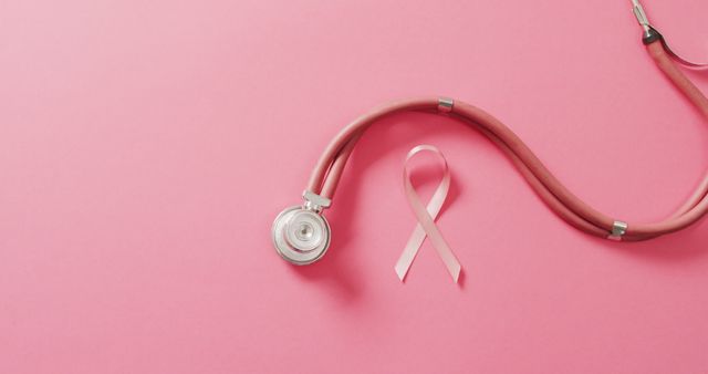 Image of stethoscope and pink ribbon on pink background. health, prevention, medicine, symbols and cancer awareness concept.