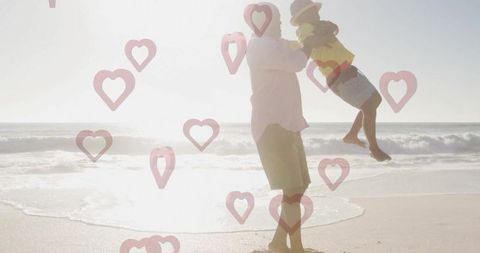 Father Lifting Son with Joyful Heart Symbols on Sunny Beach