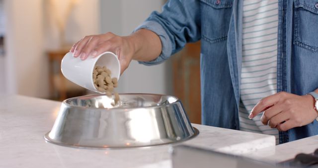 Person Pouring Dog Food into Stainless Steel Bowl on Kitchen Countertop - Download Free Stock Images Pikwizard.com