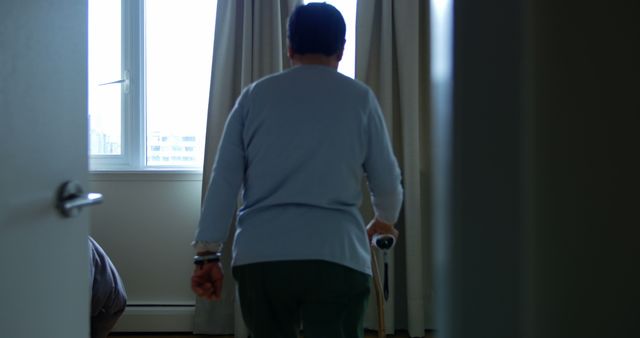 Elderly person using walking cane in dimly lit room - Download Free Stock Images Pikwizard.com