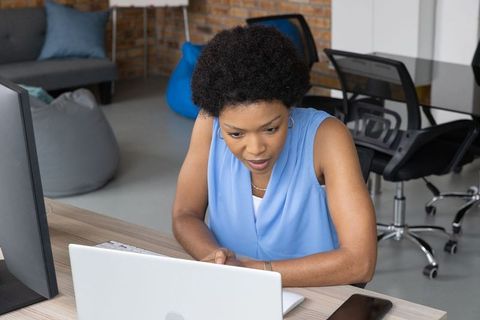 Focused African American Professional Utilizing Laptop in Modern Office