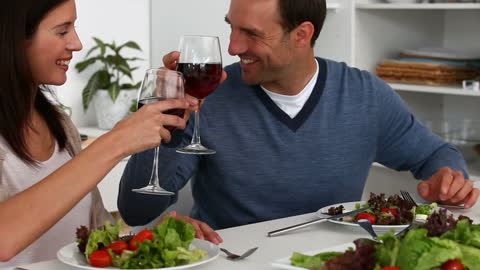 Couple Enjoying Lunch with Red Wine at Home Kitchen Table
