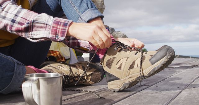 Low section of caucasian woman camping, sitting outside tent putting on boots in rural setting. healthy living, off grid and close to nature.