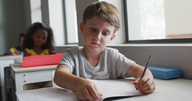 Image of focused caucasian boy doing lessons in classroom. primary school education and learning concept.