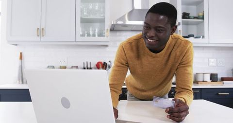 Man Online Shopping in Modern Kitchen with Laptop and Credit Card