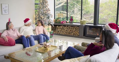 Multi-generational family gathering around Christmas tree in cozy modern living room