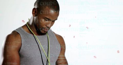 Male athlete standing, tilting head and checking neon cords wearing tank top and lanyard