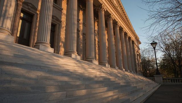 Neoclassical civic hall with monumental staircase and fluted columns at golden hour