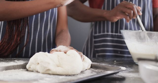 Diverse couple kneading bread dough in kitchen, wearing striped aprons - Download Free Stock Images Pikwizard.com