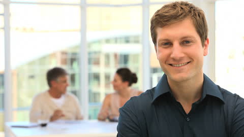 Confident Businessman Smiling with Colleagues in Background