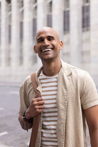 Smiling african man carrying shoulder bag on city street casual summer outfit