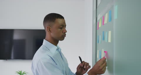 Focused Professional Analyzing Colorful Sticky Notes in Modern Office