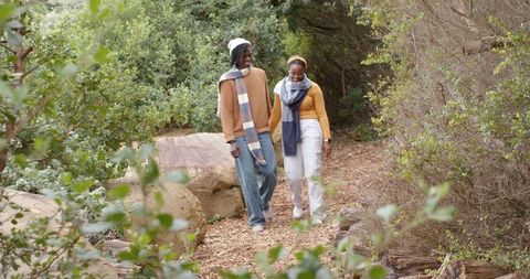 African American Couple Walking Along Woodchip Trail in Wooded Park Wearing Scarves