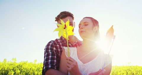 Joyful Young Couple Embracing with Colorful Pinwheels Outdoors