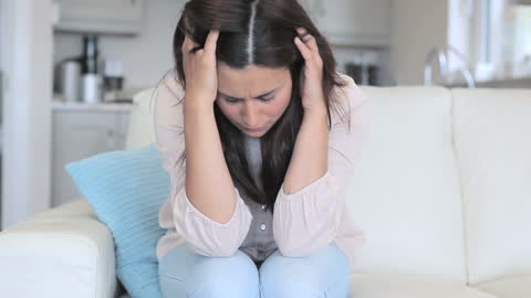 Stressed Woman Sitting on Sofa Appear Troubled and Anxious
