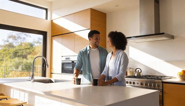 Sunlit modern kitchen couple sipping coffee and sharing conversation at marble island