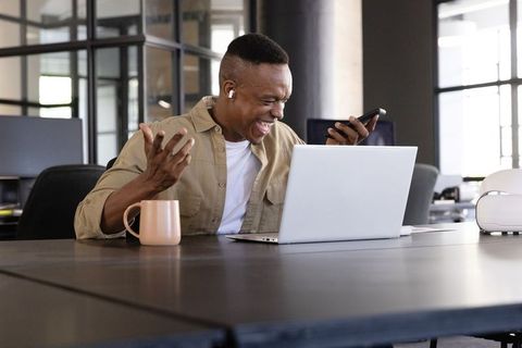 Businessman enthusiastically engaged in phone conversation at office desk