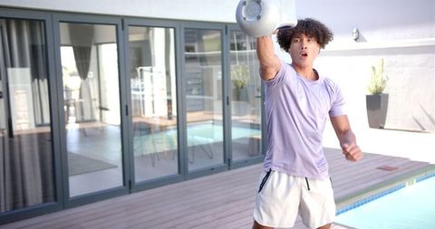 Man Engaged in Outdoor Kettlebell Workout by Swimming Pool