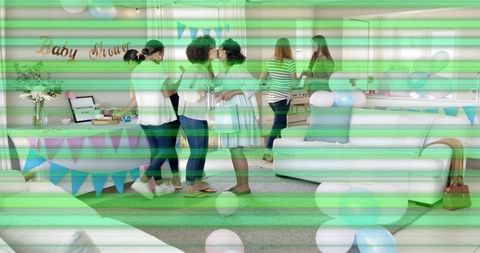 Women celebrating baby shower, expectant mother kissing friend, pastel balloons and gifts