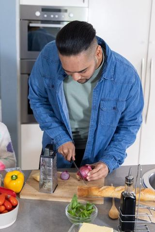 Asian man chopping red onion on kitchen counter preparing homemade meal